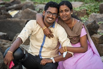 Woman hugging man with mobile phone, young married Indian couple, Fort Cochin, Kochi, Kerala, South