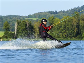 Young man doing sports with wakeboard in lake, water sports, water skiing in wakepark, Stráž pod