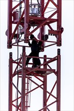 Erection of a construction crane, part of the upper crane section is hoisted by mobile crane onto