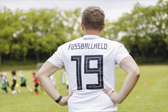 Volunteer coach trains children on the football pitch, Bonn, 19.06.2024