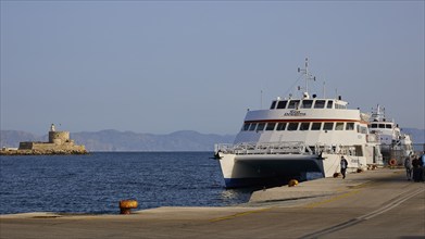 People at a harbour with ferry and old coastal fortification in the background, Fort of Saint