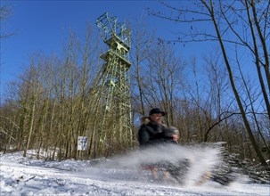 Winter in the Ruhr area, toboggan run on a forest path at Lake Baldeney, headframe of the former