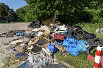 Illegally disposed waste, car tyres, building rubble, household waste, clothing, on a path next to