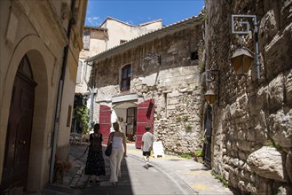 Holidaymakers walk through a historic alley in Arles, Provence-Alpes-Côte d'Azur, France, Europe