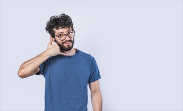 Attractive young man imitating telephone conversation isolated. Young man in glasses making calling