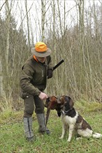 Hunter with shot pheasant (Phasianus colchicus) retrieved by hunting dog Kleiner Münsterländer,