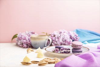 Purple macarons or macaroons cakes with cup of coffee on a white and pink background and