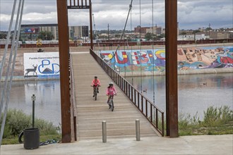 Pueblo, Colorado, Bicycle riders cross a bridge over the Arkansas River where murals and a bike