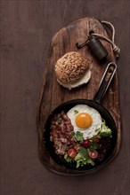 Fried egg, with bacon and vegetables, in a cast-iron frying pan, top view, homemade breakfast