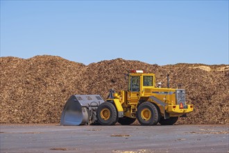 Loader at big stacks of woodchips for solid biomass fuel, Sweden, Europe