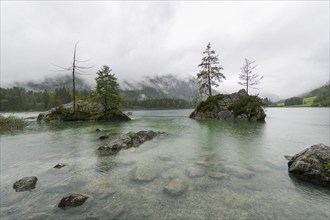 Hintersee near Ramsau, surrounded by forests and mountains under a cloudy rainy sky, fog,