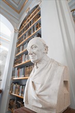 Bust of a historical scholar in front of a bookshelf in an impressive library, Weimar, Germany,