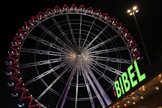 Night shot, sales stand for Bibles, religion, neon sign, Ferris wheel, Bible, behind it Ferris