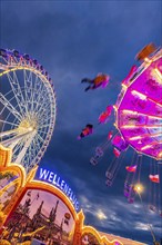 Chain carousel and Ferris wheel in the evening. 177th Cannstatter Volksfest at the Cannstatter