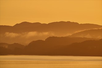 Atmospheric landscape scene at sunrise, landscape in twilight with soft fog, calm sea, Bergen,