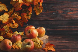 Apples and autumn leaves on dark wood create a warm autumn atmosphere