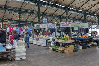 Busy indoor market filled with vegetable and clothing stalls and people, Belfast