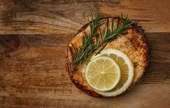 Salmon steak, fried, on a cutting board, top view, rosemary, lemon and lime, homemade, one serving,