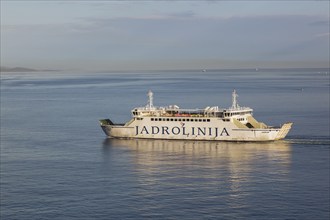 White and blue Jadrolinija Jadran Rijeka ferry boat on calm Adriatic sea leaving Port of Zadar in