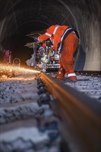 Worker welding on a rail in a tunnel while sparks fly, rail welding, track construction Hermann