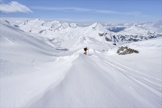 Ski tourer in mountain landscape with snow, behind summit Mittaghorn and Wildhorn, ascent to