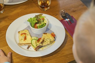 Toast with cheese and salad garnish, a child reaches for the plate, autumn creations, Cafe Kuh,