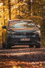 Car in autumn forest with golden leaves, electric car VW ID5, Gechingen, Black Forest, Germany,