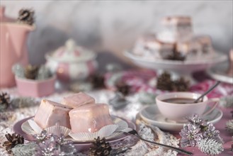 Pink glazed cakes, punch doughnuts and coffee on a table decorated in pink and white for Christmas