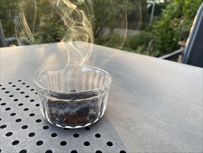 Coffee in a glass jar, on a table, lit, burning, smoking, to repel wasps, Stuttgart,