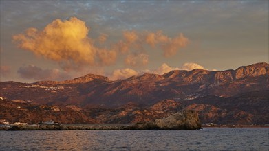 Sunrise on the coast with dramatic cloud formations and mountain landscape in the background,