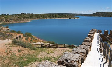 Idyllic view of a large lake with clear water and surrounding landscapes under a blue sky, Embalse