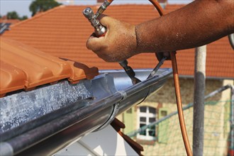 Roofer doing tinsmith work on a gutter