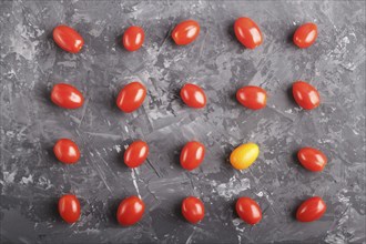 Rows of cherry tomatoes and one kumquat on a black concrete background, top view, flat lay.