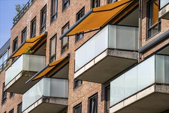 Residential building, flat with balconies and orange sun protection blinds, balcony awning