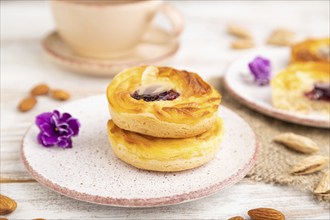 Small cheesecakes with jam and almonds with cup of coffee on a white wooden background and linen