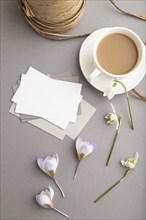 White paper business card mockup with spring snowdrop crocus and galanthus flowers and cup of