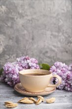 Cup of coffee with lilac and almonds on a gray wooden background. Side view, copy space. selective