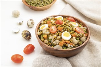 Mung bean porridge with quail eggs, tomatoes and microgreen sprouts on a white wooden background