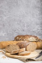 Sliced bread with different kinds of fresh baked bread on a gray concrete background. side view,