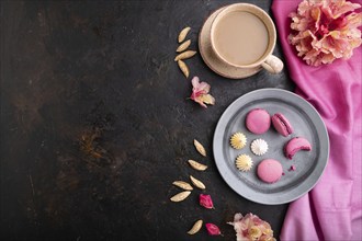 Purple macarons or macaroons cakes with cup of coffee on a black concrete background and pink