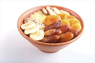 A plate with muesli, banana, dried apricots, dates, Brazil nuts isolated on a white background.