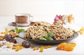 Homemade granola from oat flakes, dates, dried apricots, raisins, nuts in blue ceramic plate with a