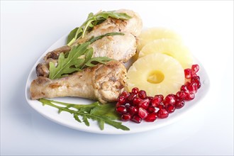 Fried chicken legs with rucola, pineapple and pomegranate seeds isolated on white background, close