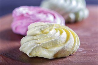 Colored meringues on wooden board, selective focus, close up