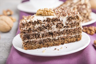 Homemade cake with milk cream and walnuts with cup of coffee on a gray concrete background and