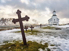 Gimsøy church with cemetery, snow-covered mountains in the background, winter, Gimsøya, Lofoten,