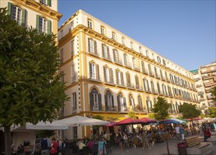 People sitting outside popular cafes on a sunny afternoon in Plaza de la Merced, Malaga, Spain,