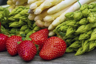 Green asparagus, white asparagus and fresh strawberries decorated on a rustic wooden table