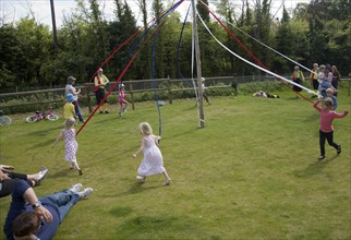 Children dance around a maypole at an English country festival, Shottisham, Suffolk, England,