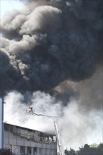 Two firefighters with protective clothing and gas masks in aerial work platform, lifting platform